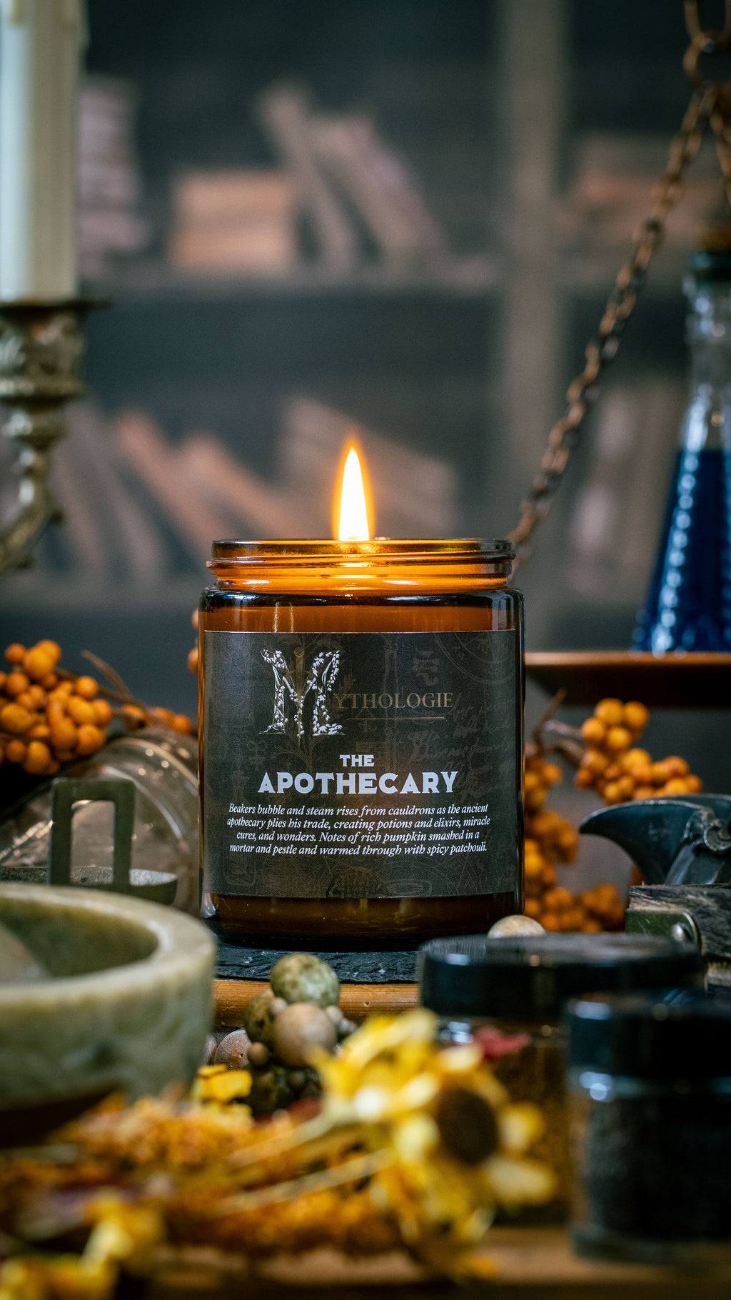 Apothecary pumpkin and patchouli coconut wax candle by Mythologie Candles beside a mortar and pestle and glass beakers (image 2)